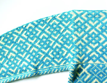 russian prime motif on a sleeve and partial body of sweater in blue and cream