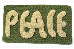 knitted word peace in cream script on green background