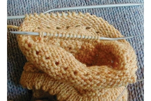 yellow cuff in progress with stitches on needle