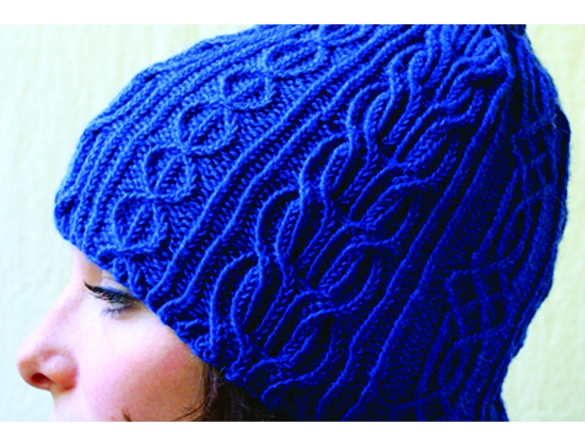Close up of a twisted stitch/cabled hat, bright blue worn by a young woman with only part of her face showing