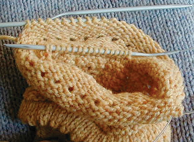 yellow cuff in progress with stitches on needle