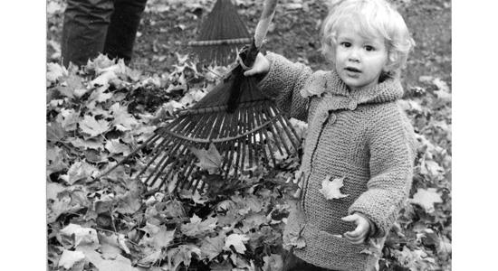 boy in Tomten sweater with rake and leaves, black and white photo