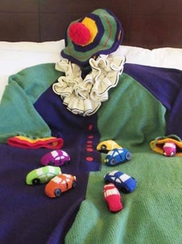 knitted clown suit in blues, greens, with knitted tiny clown cars