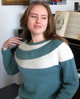 young woman wearing ebb and flow sweater in eucalyptus and natural white, wave yoke